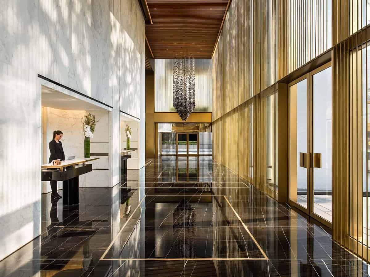Lobby area with white marble walls, black tiled floors, gold accents and a receptionist at her desk