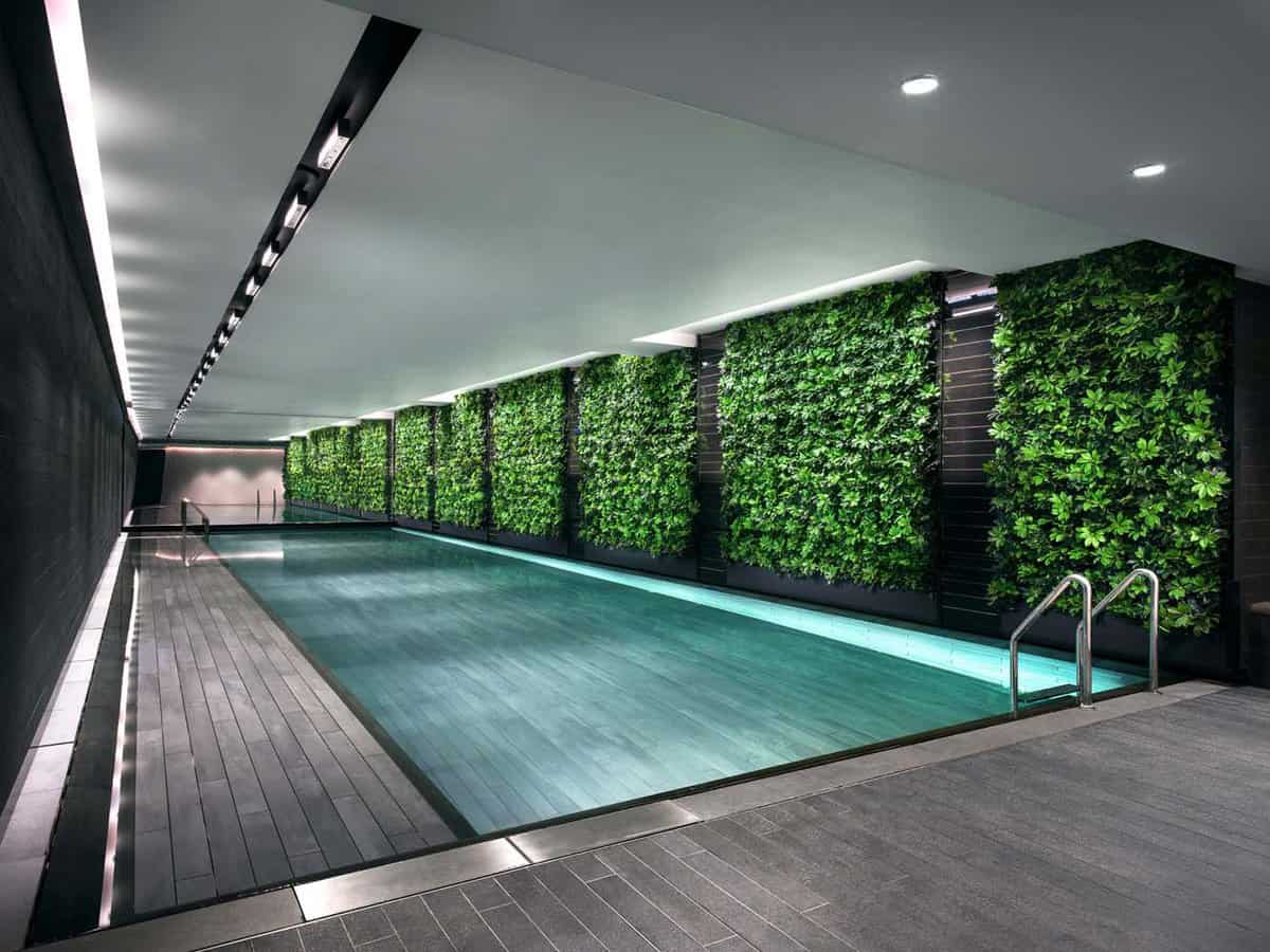 Sleek indoor pool area with black wooden panels and a living wall opposite
