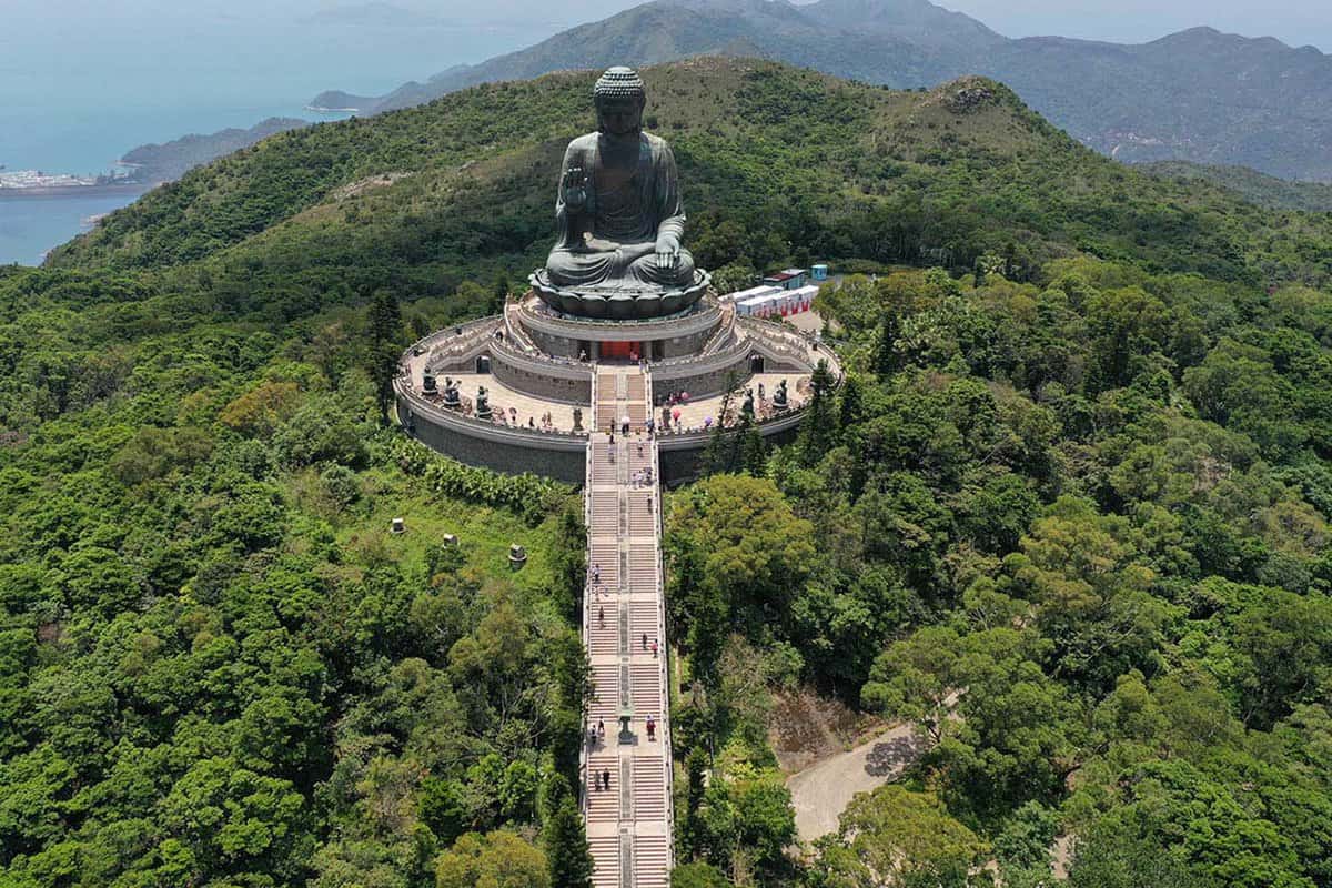 The giant Tian Tan Buddha, with steps leading up to the top amid lush greenery