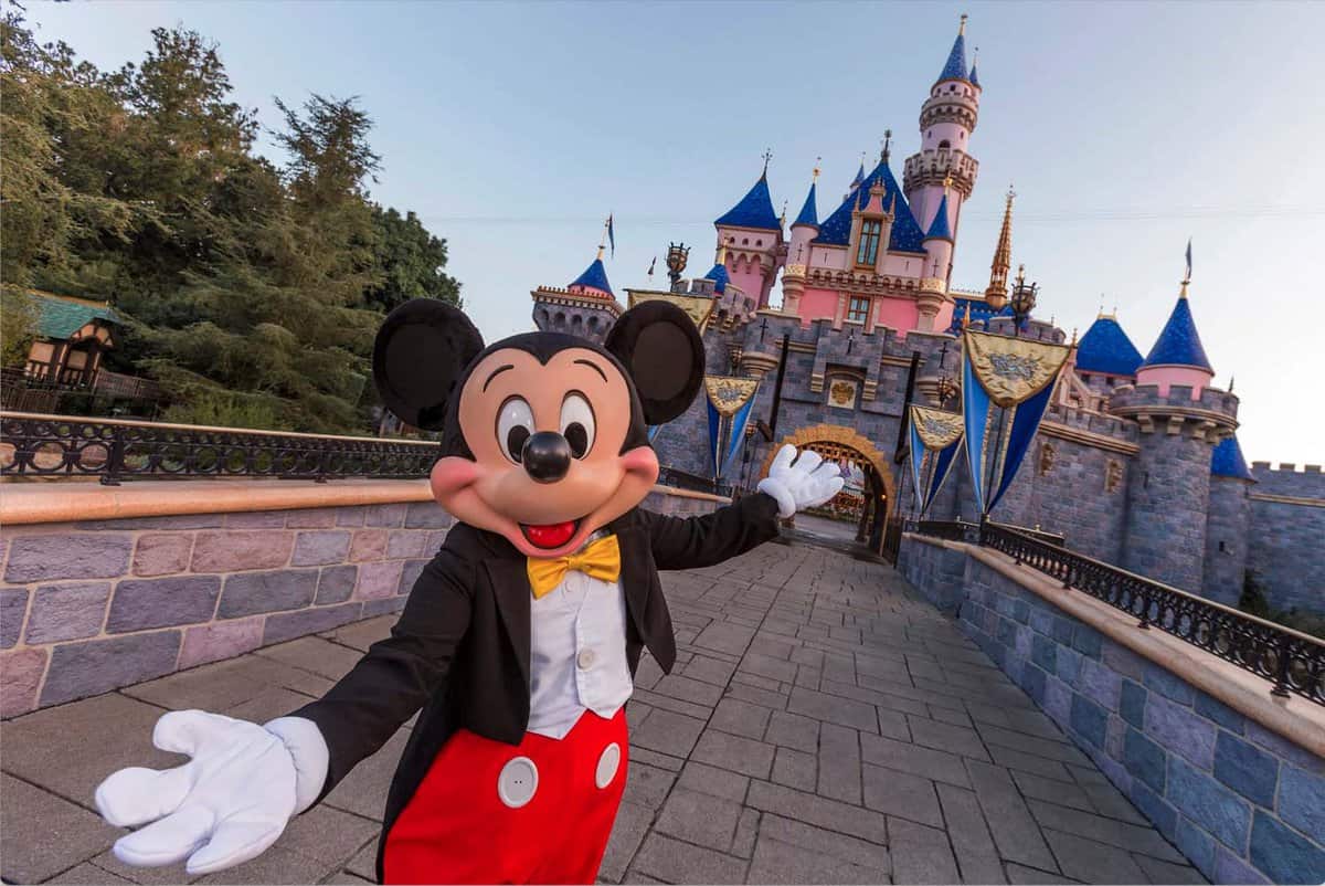 Mickey Mouse in front of the Disney castle at Disneyland