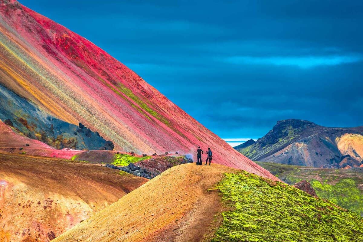two figures admire colourful hills in Landmannalaugar National Park