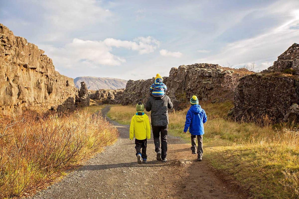 Father with three children, enjoying a sunny day in Thingvellir National Park rift valley, Iceland autumn time
