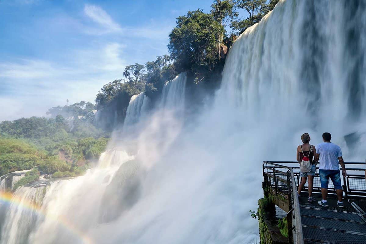close up of a couple standing on a viewpoint next to Iguazu Falls