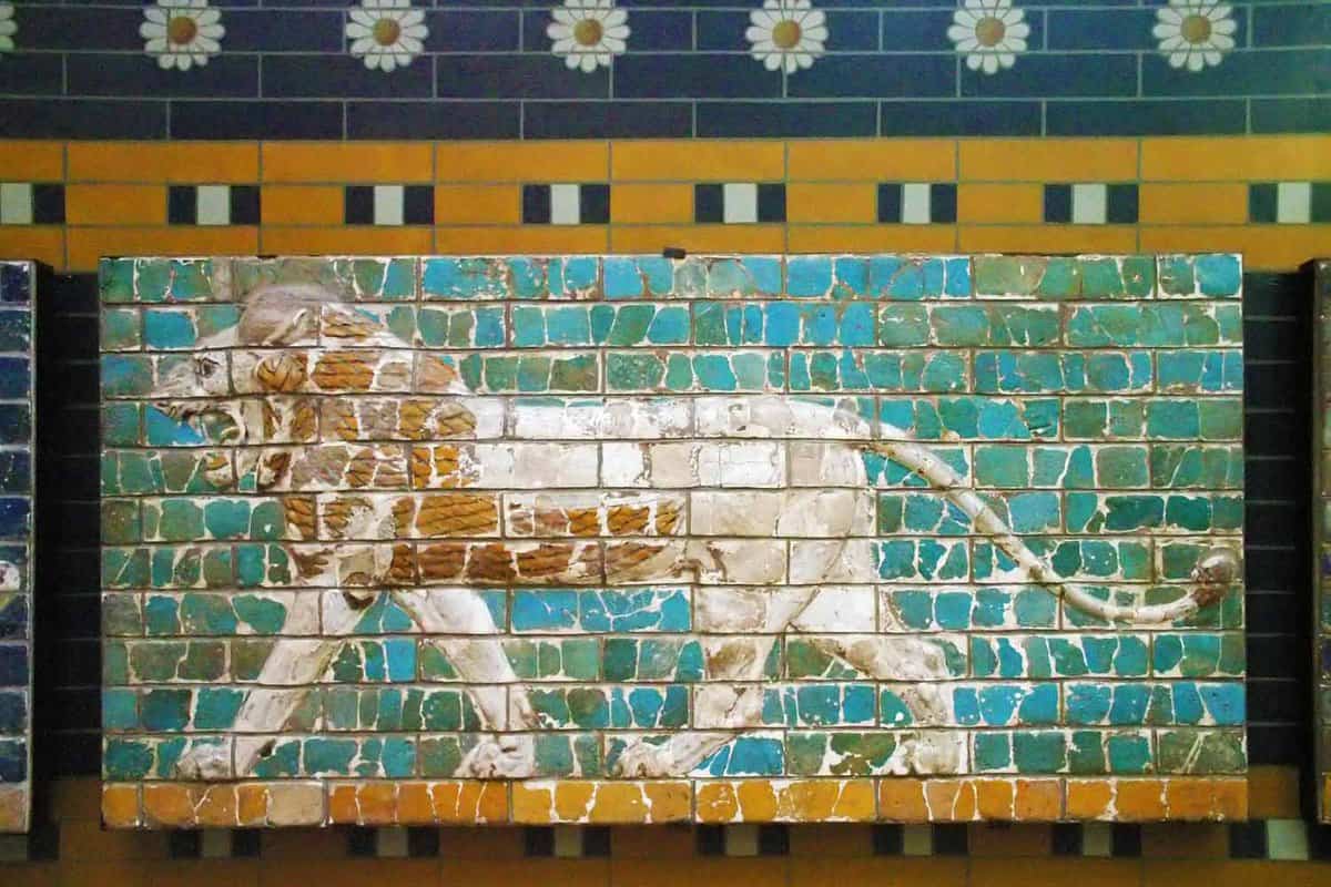Mosaic of a lion walking against a green and blue background