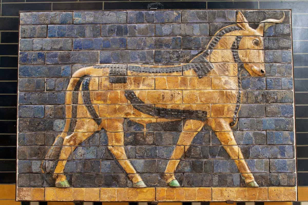 A mosaic of a bull walking against a blue backdrop