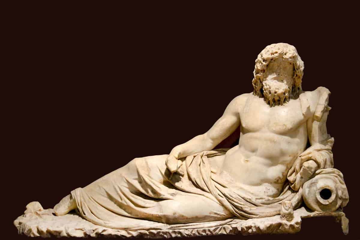 Marble statue of Oceanus, a bearded and long-haired man, reclining against a black background