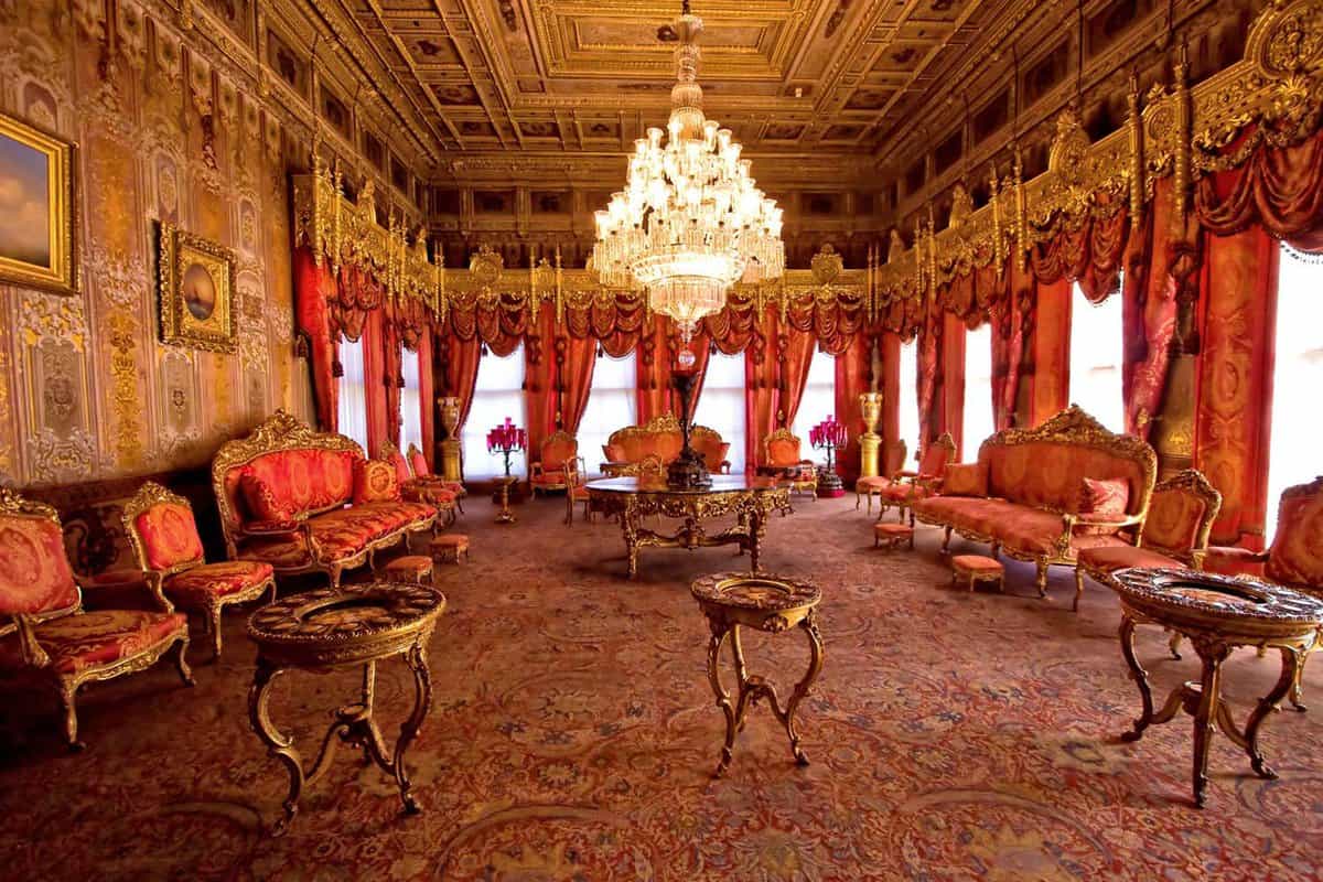 Palace room with chandelier hanging above plush red sofas