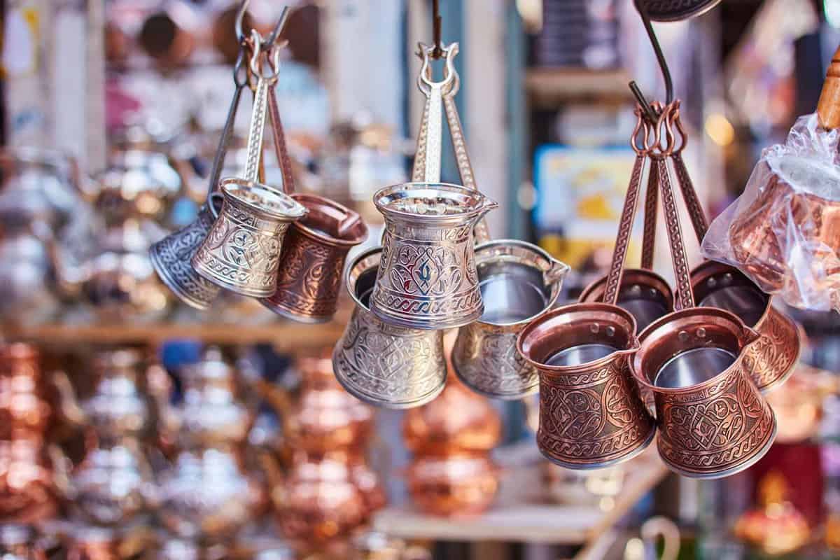 Close-up of traditional copper and silver Turkish coffee and tea makers hanging from hooks