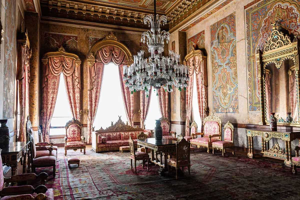 Ornate palace interior with chandelier, sofas and curtained windows