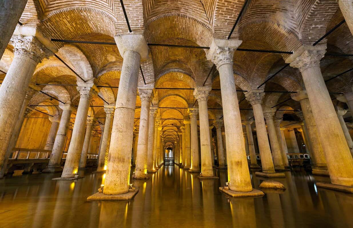 Columns in a large cistern with water on the ground reflecting cieling
