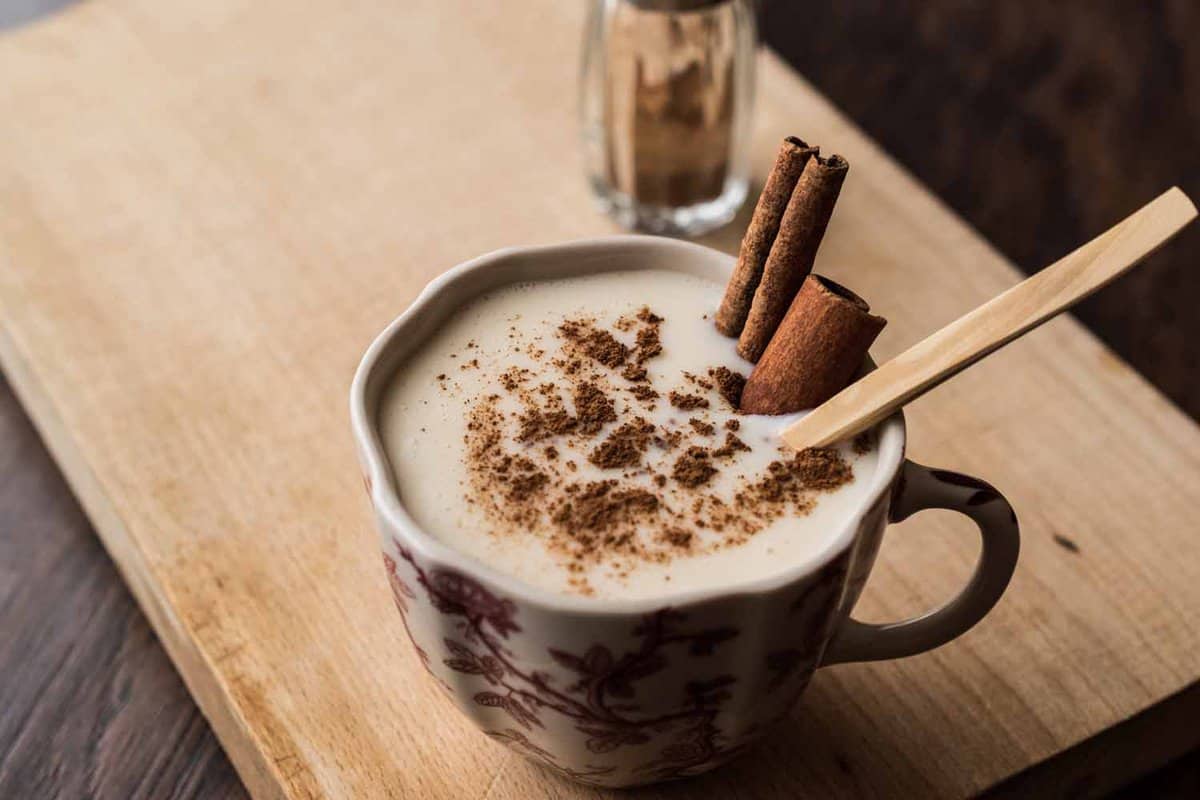 A ceramic mug of a traditional Turkish milk drink with cinnamon sticks and a stirrer sticking out of the cup