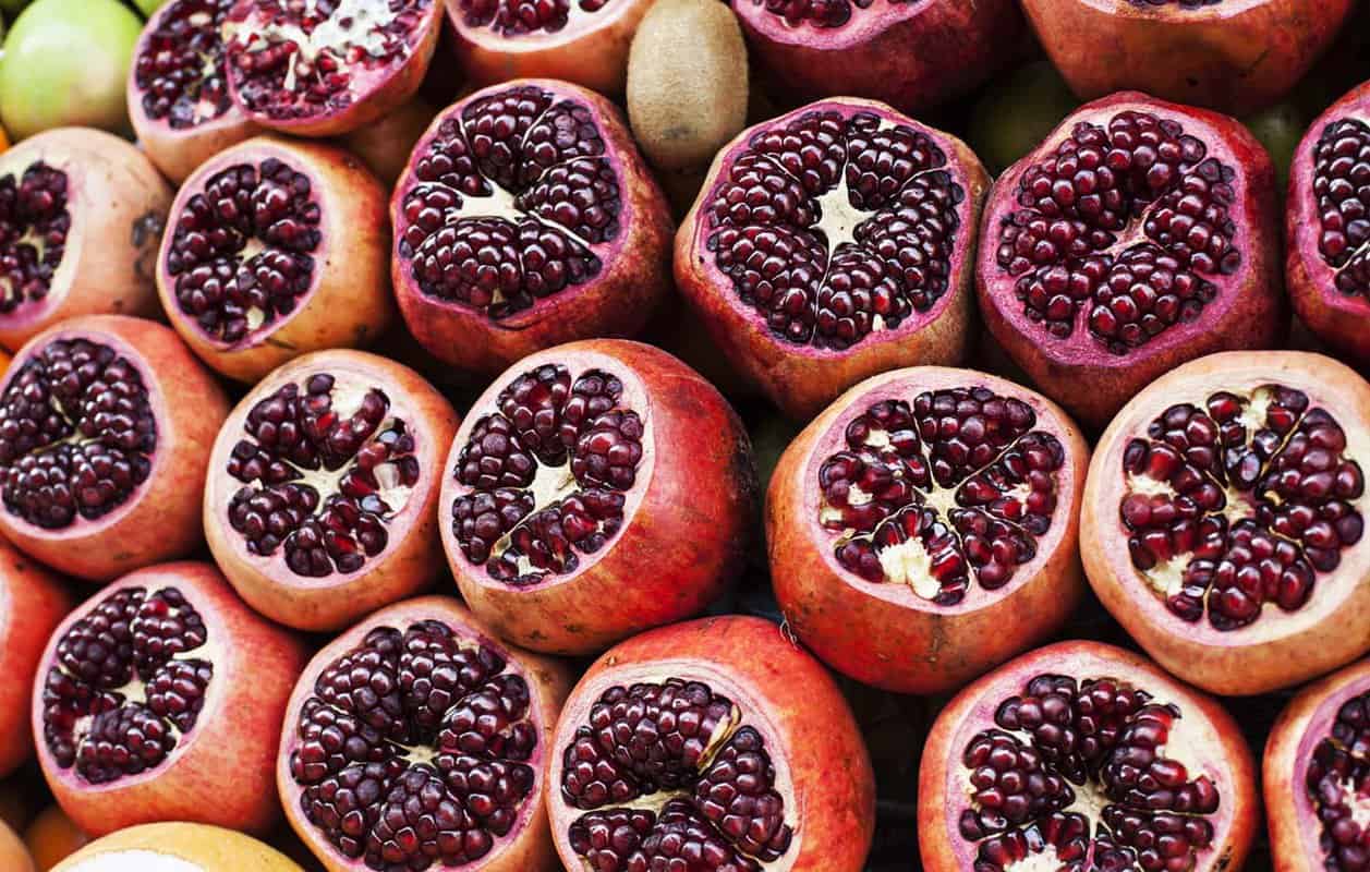 Close-up photo of cut pomegranates packed together at a street stall