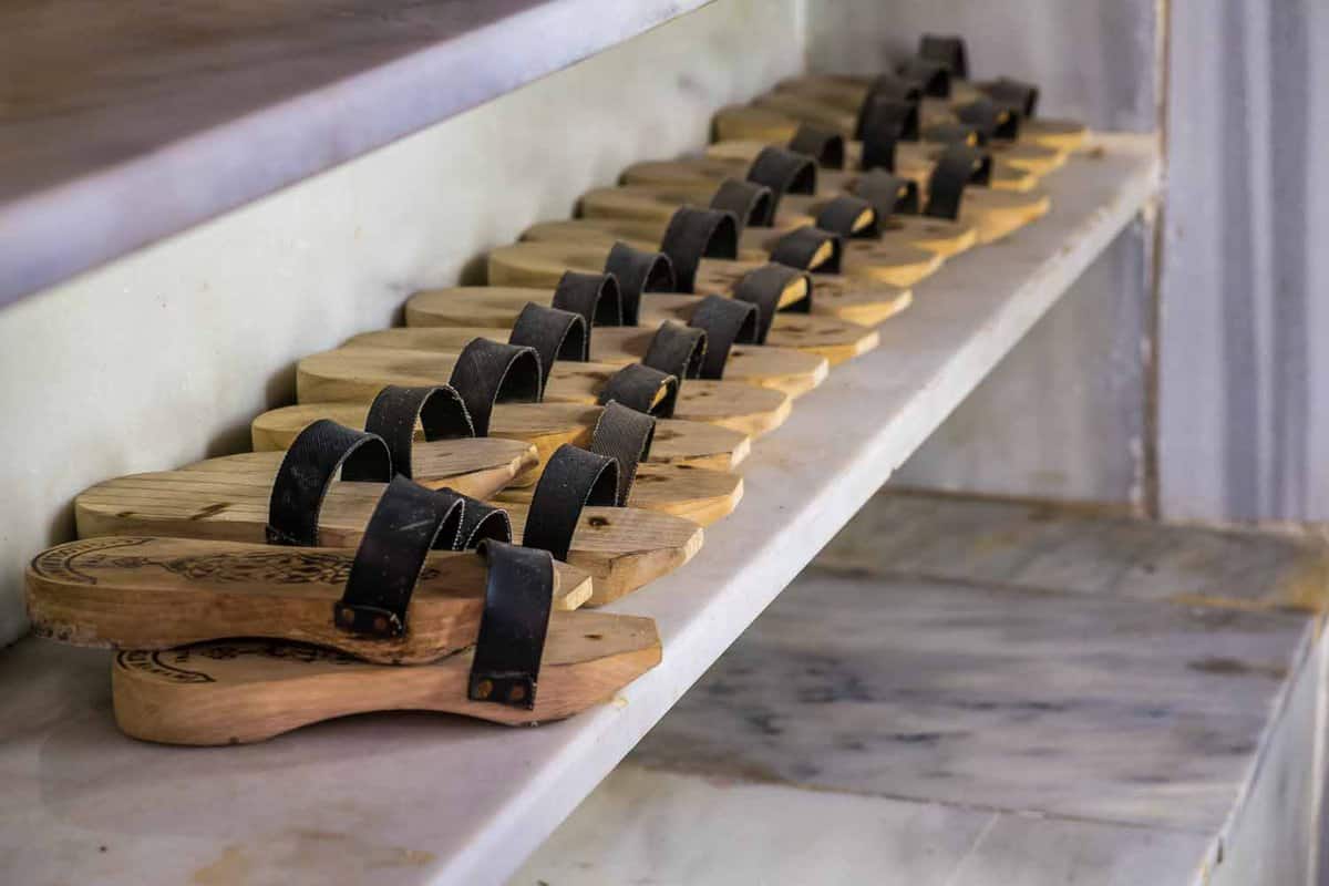 A row of tan slippers with brown leather straps on a shelf