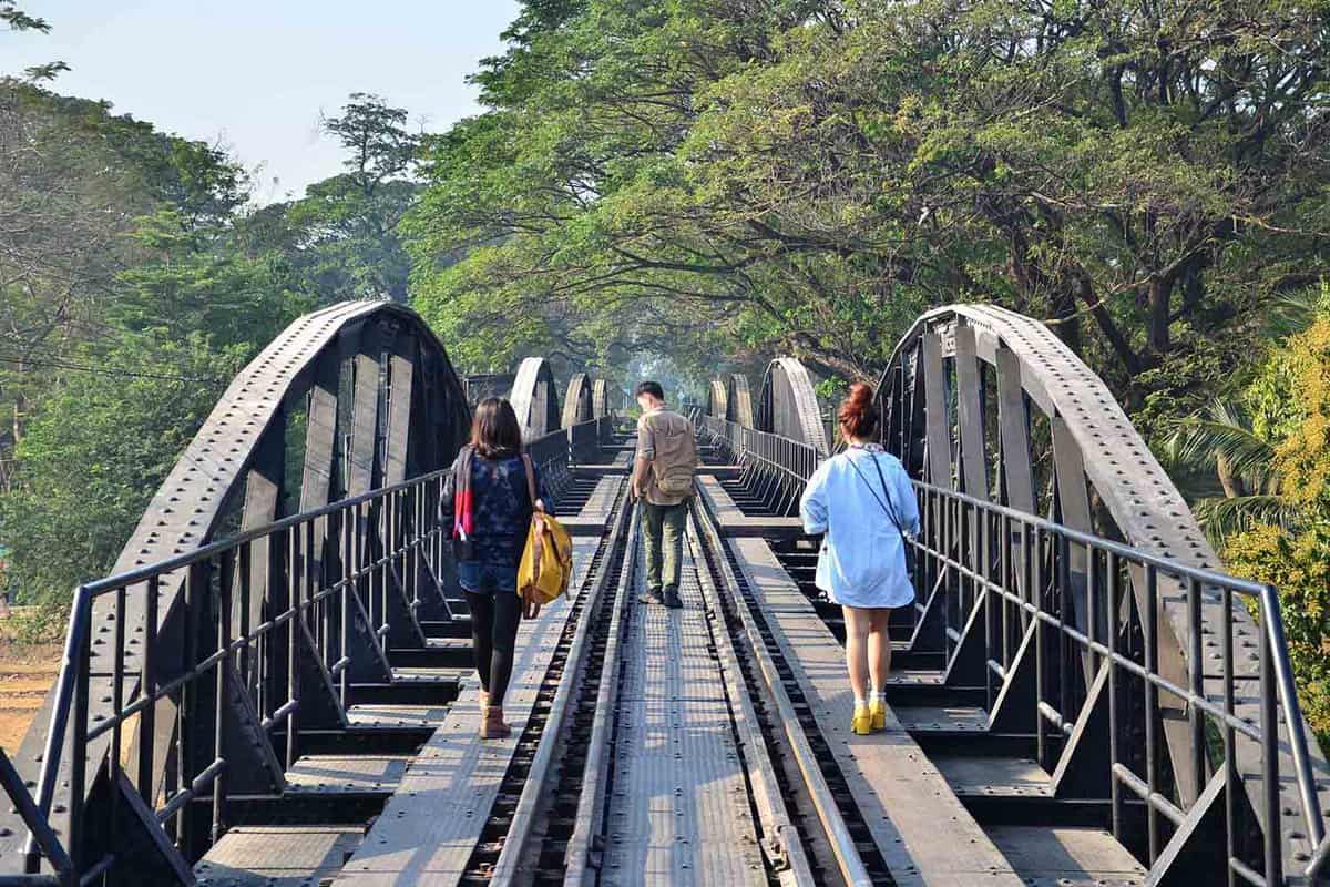 Tourists walking on metal tracks on bridge