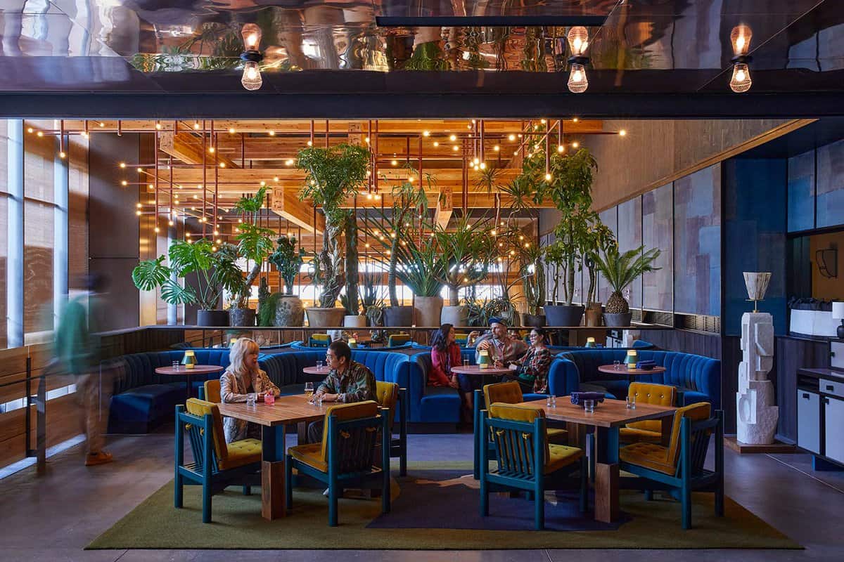tables and chairs with tall plants in hotel lobby