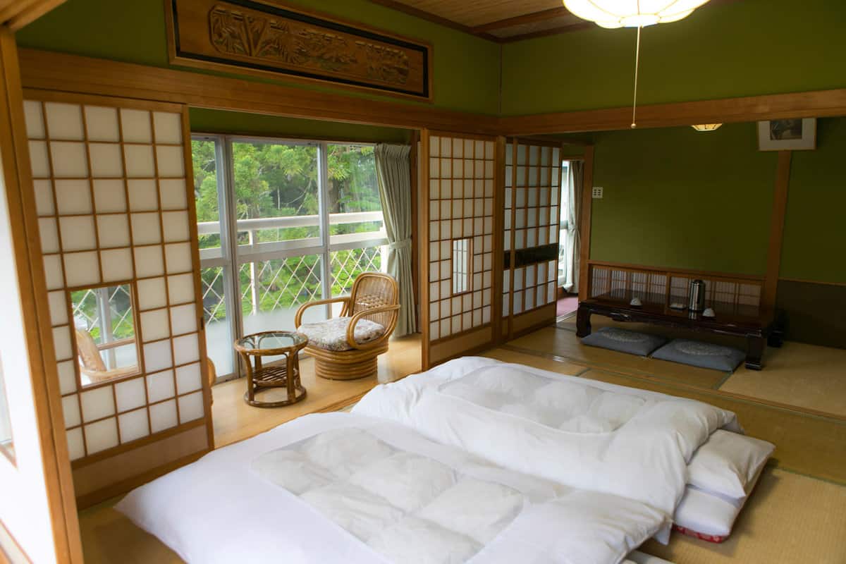 Inside of a traditional Japanese bedroom with shoji open to nature