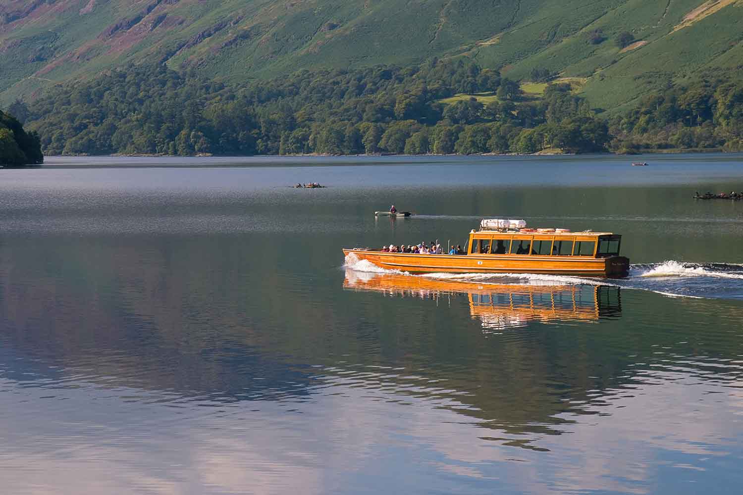 a wooden boat travelling across a lake