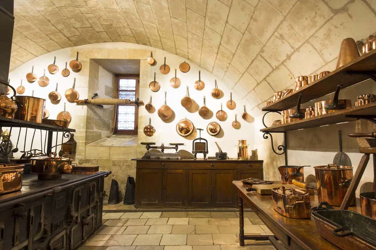 Kitchen of the chateau, with brass pots on the walls and workbenches