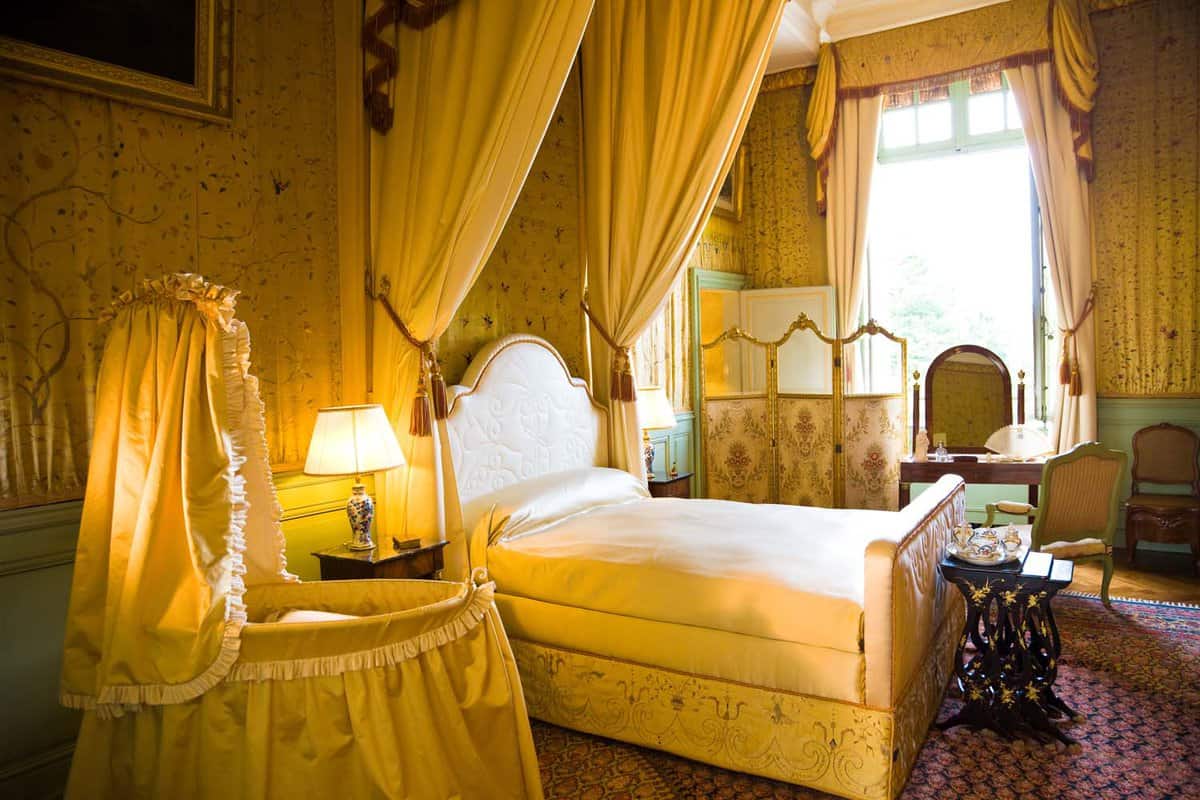 Old-fashioned, yellow bedroom with double bed and cot