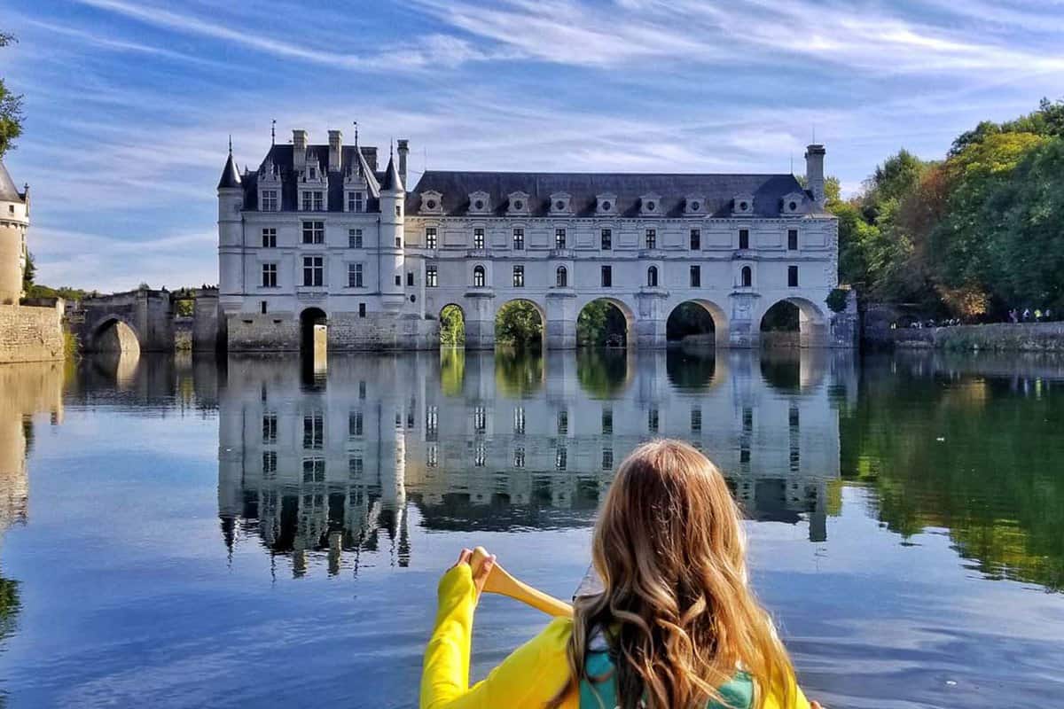 A view of Chateau Chenoncea from the river where a girl is kayaking