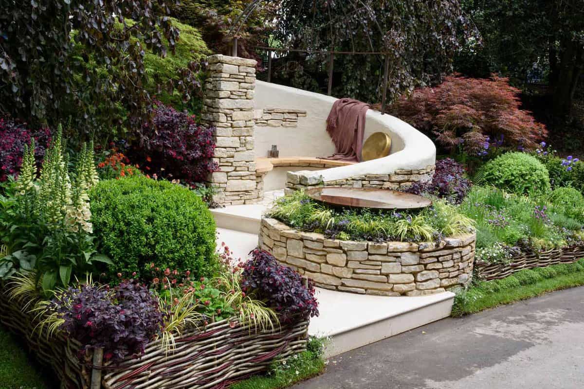 Close up of a stone circular seating area surrounded by shrubs