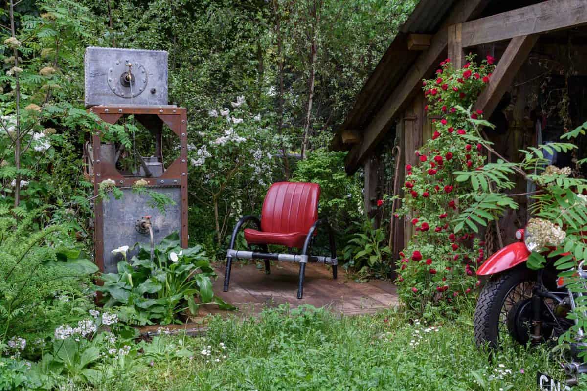 A bright red armchair in the middle of a small garden