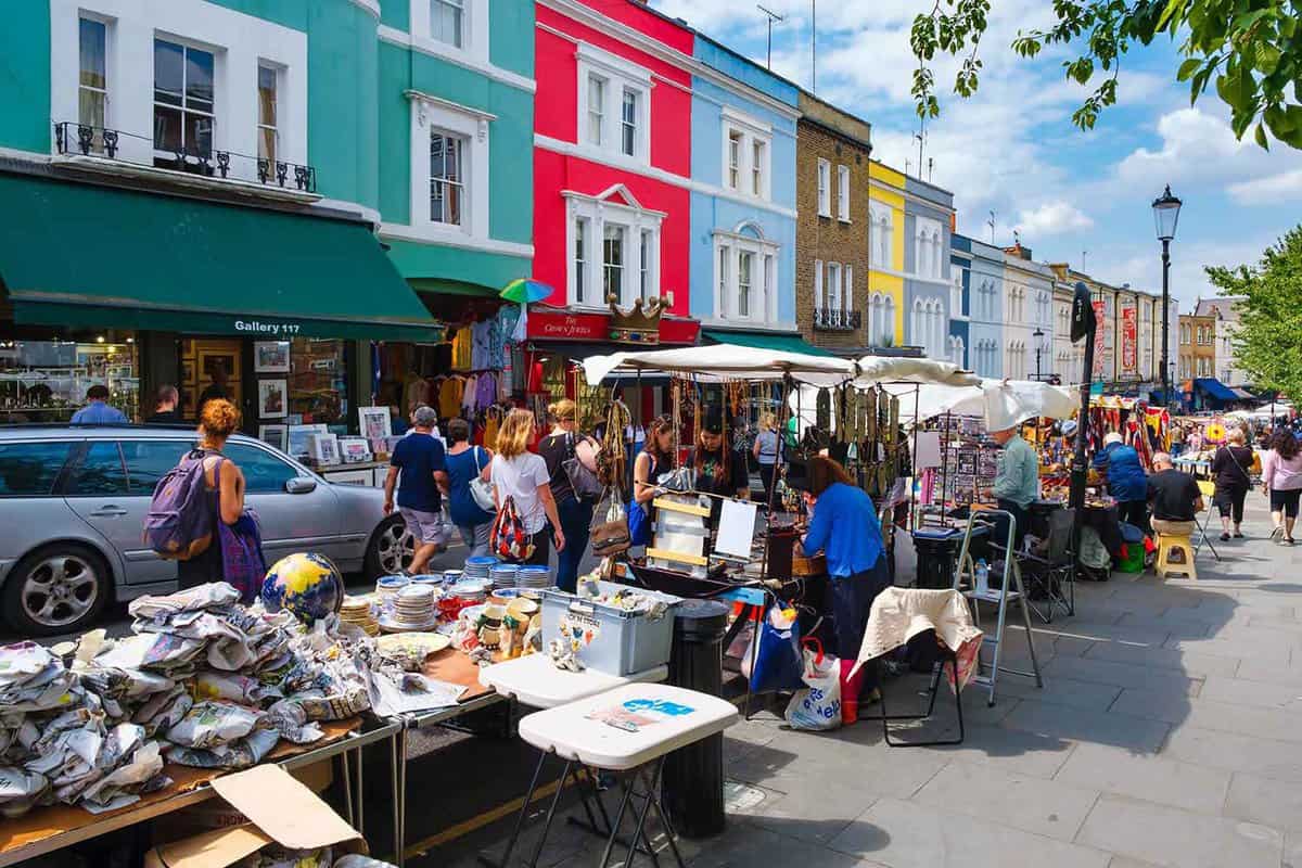 Street view of a market with stalls selling bric-a-brac, colourful houses behind