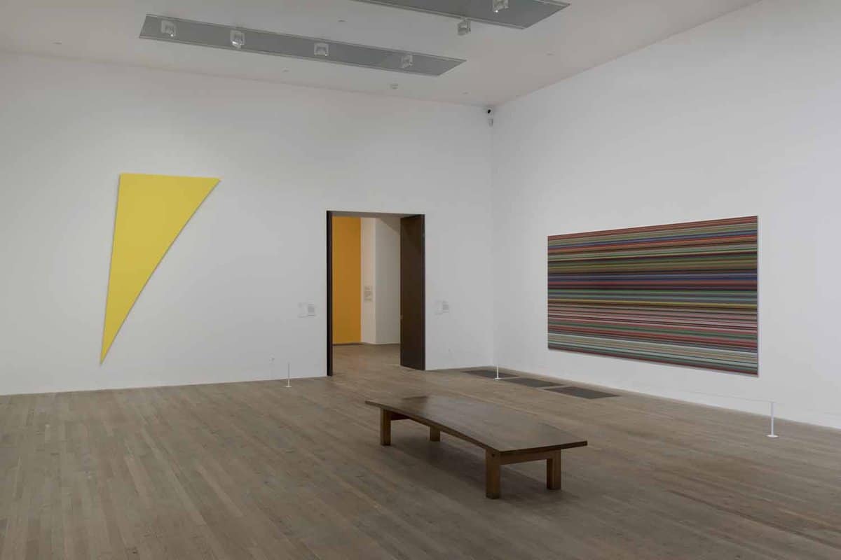 A plain white display room showing a large striped painting