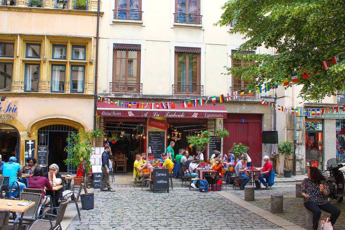 Exterior of a cafe on a square in a traboule, people sitting outside