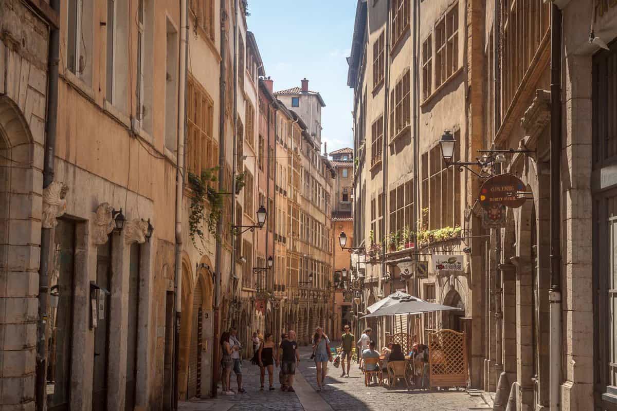 Typical narrow street of the Vieux Lyon (old Lyon) on the Presqu'ile district with tourists passing by during a sunny summer afternoon