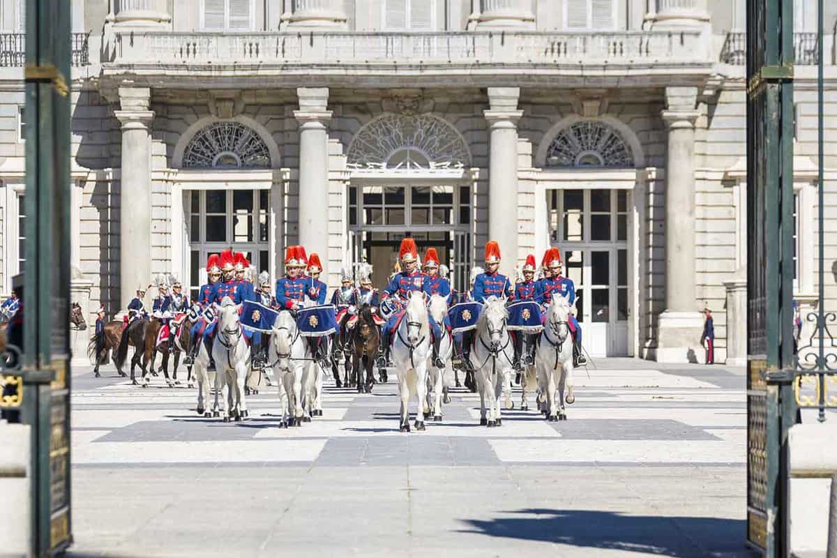 Guards on horseback walk in lines for the changing of the guard ceremony at the Royal Palace of Madrid.