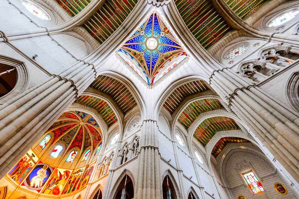The decorative ceiling of Almudena cathedral. Pale stone contrasts with a decorative blue painted element in the shape of a star.