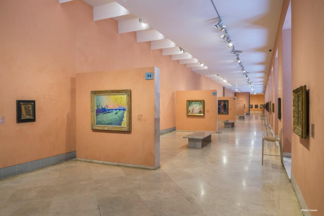 Paintings displayed on peach walls in the Thyssen-Bornemisza Museum in Madrid.