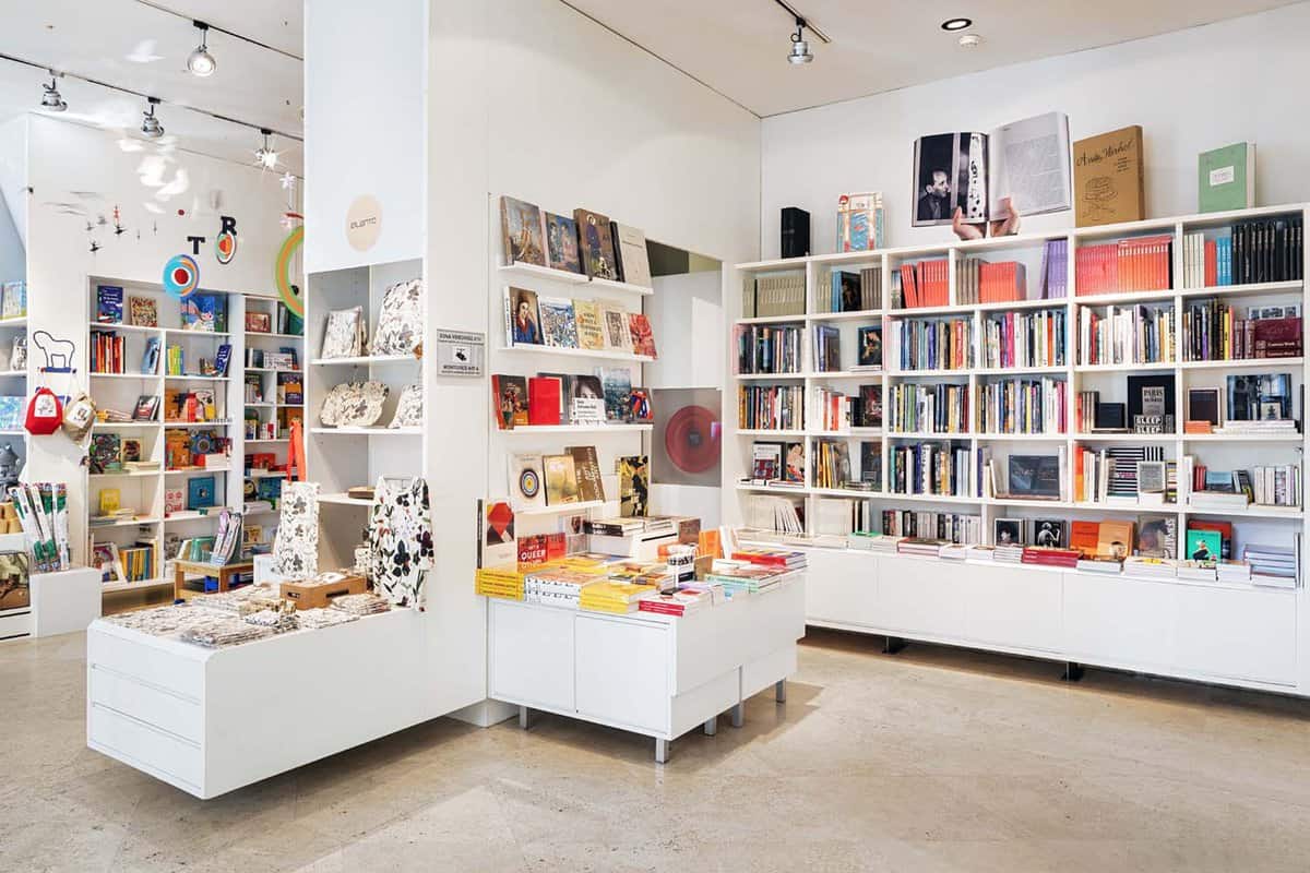The gift shop of the Thyssen-Bornemisza Museum. Books and souvenirs are displayed on white shelves.