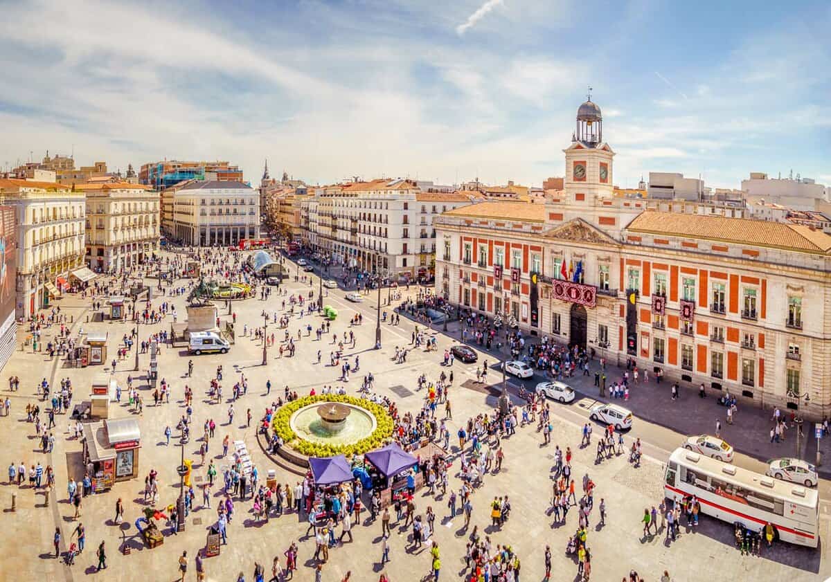 Plaza mayor seen from above. Many people walk around the Plaza, and buildings tower over it.