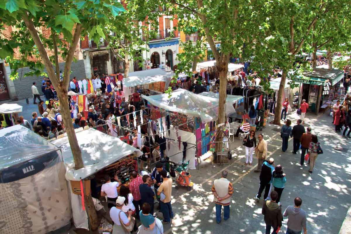 Busy market stalls with many people looking around and shopping.