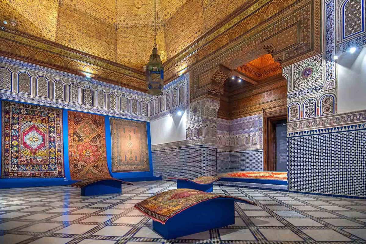 Interior of ornately-tiled museum with Moroccan carpets on display