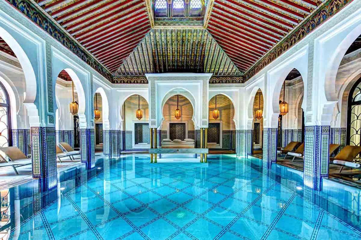 Blue-tiled indoor pool surrounded by lounge chairs