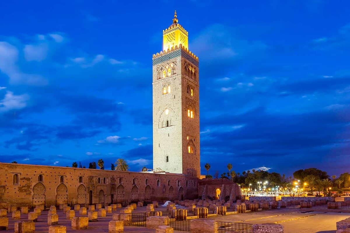 Illuminated mosque tower at night with graveyard in front