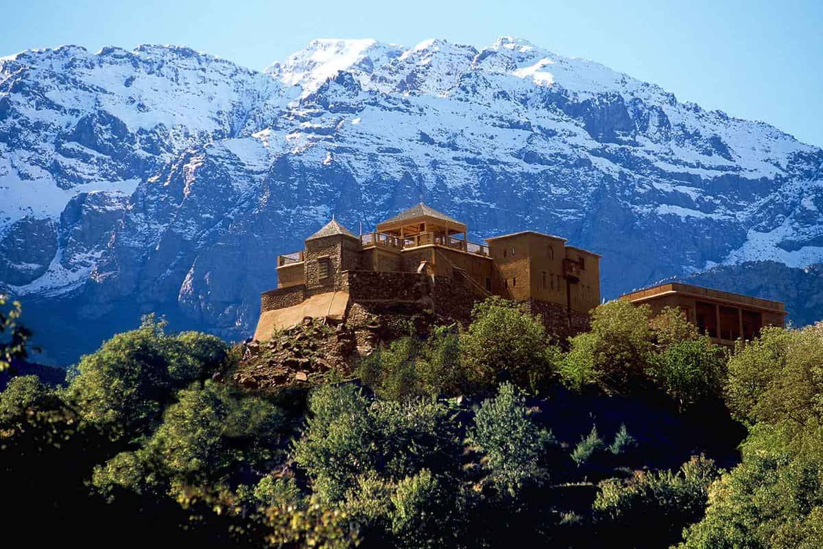 Restored kasbah on a hill in front of snow capped mountains