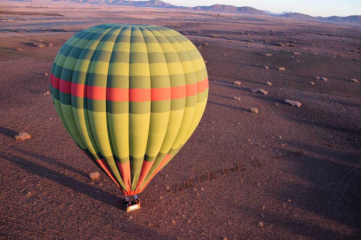 Green, yellow and red hot-air balloon flying over the desert