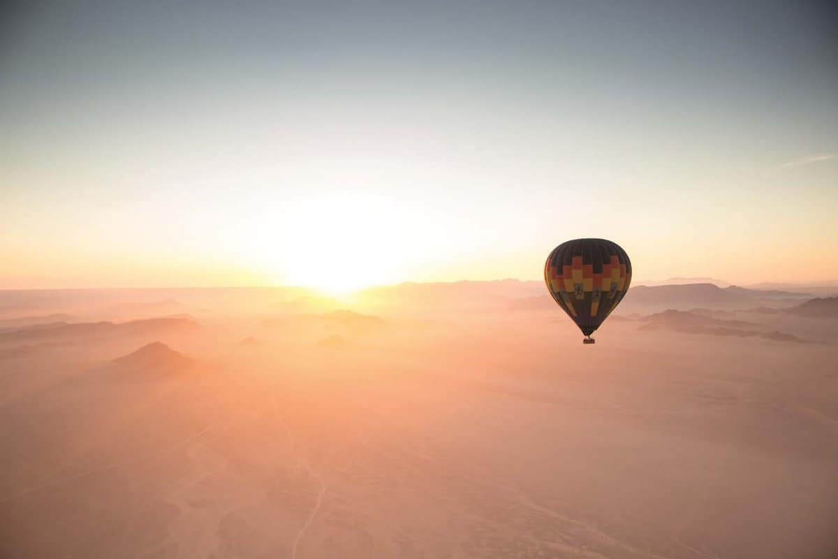 hot air balloon travelling into the sunset in the Sossusvlei Desert