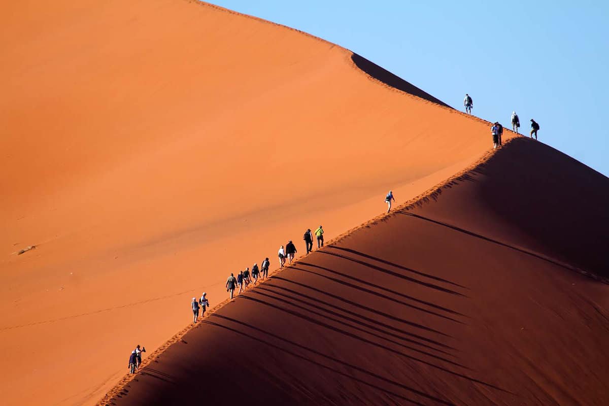A procession of tiny figures climbing up the Big Daddy dune