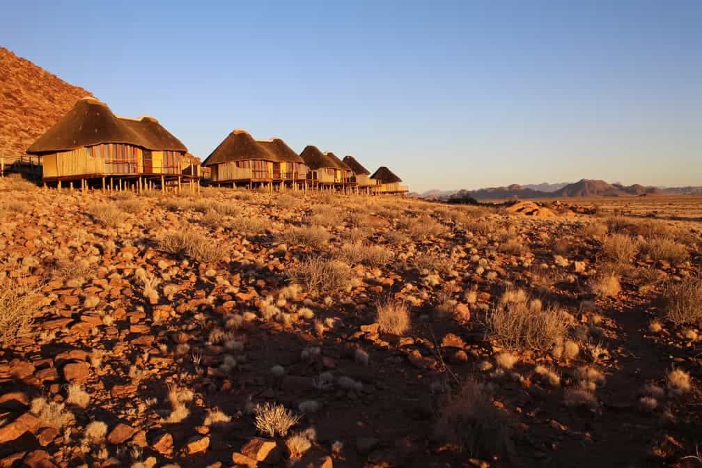 Row of thatched chalets on a desert landscape as sunset