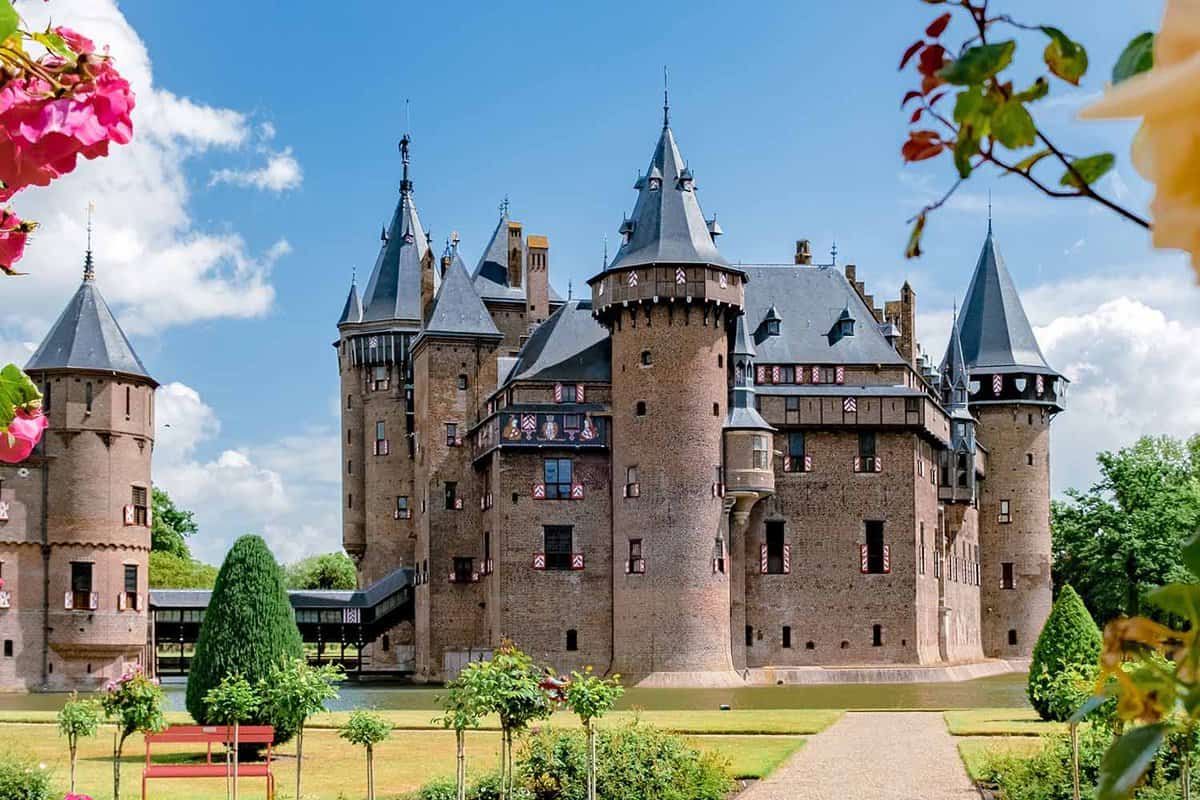 Exterior of De Haar Castle showing pink stone walls and grey turreted towers