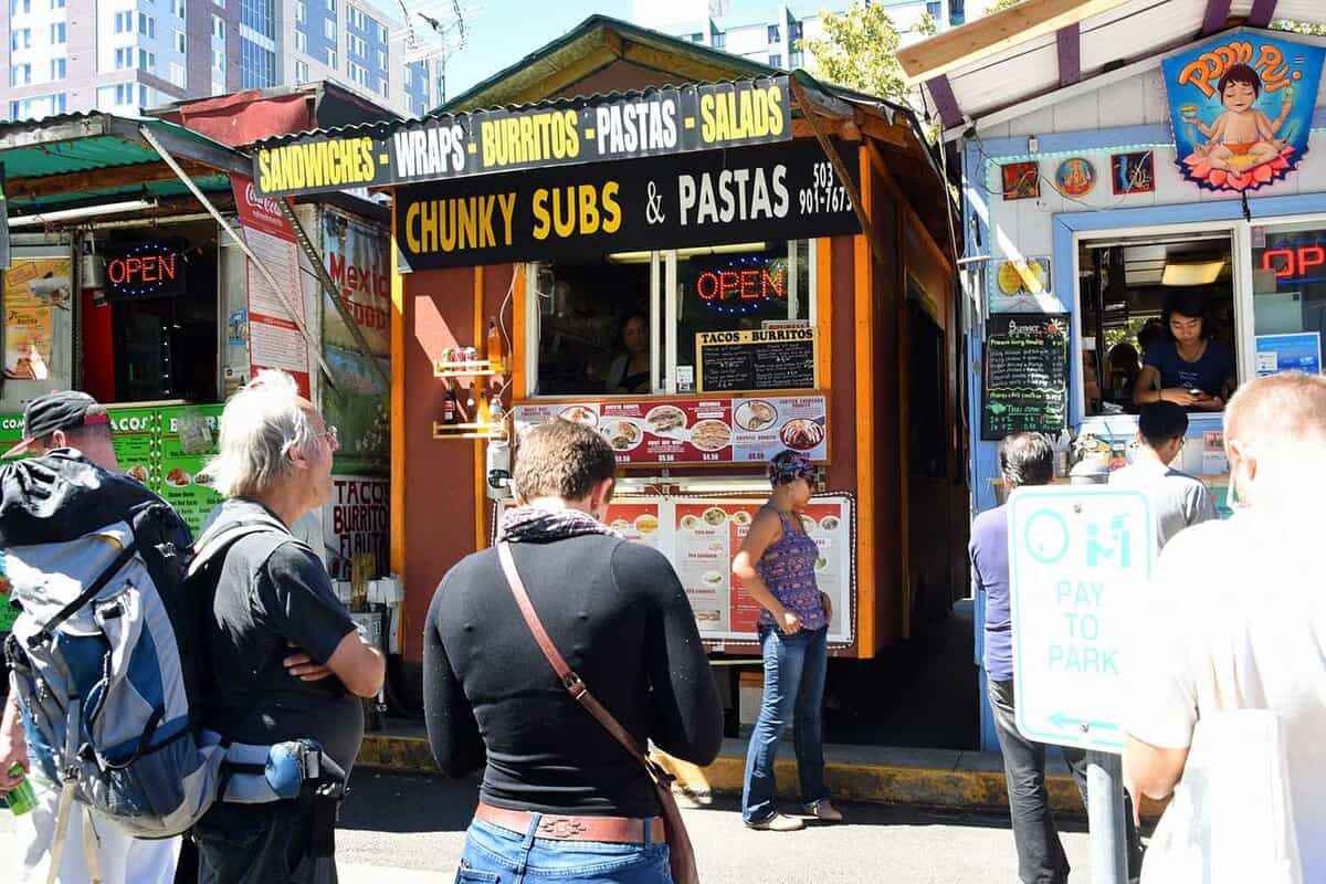 Locals and tourists wait in line to order food from food trucks in downtown Portland during lunch time in Portland, Oregon