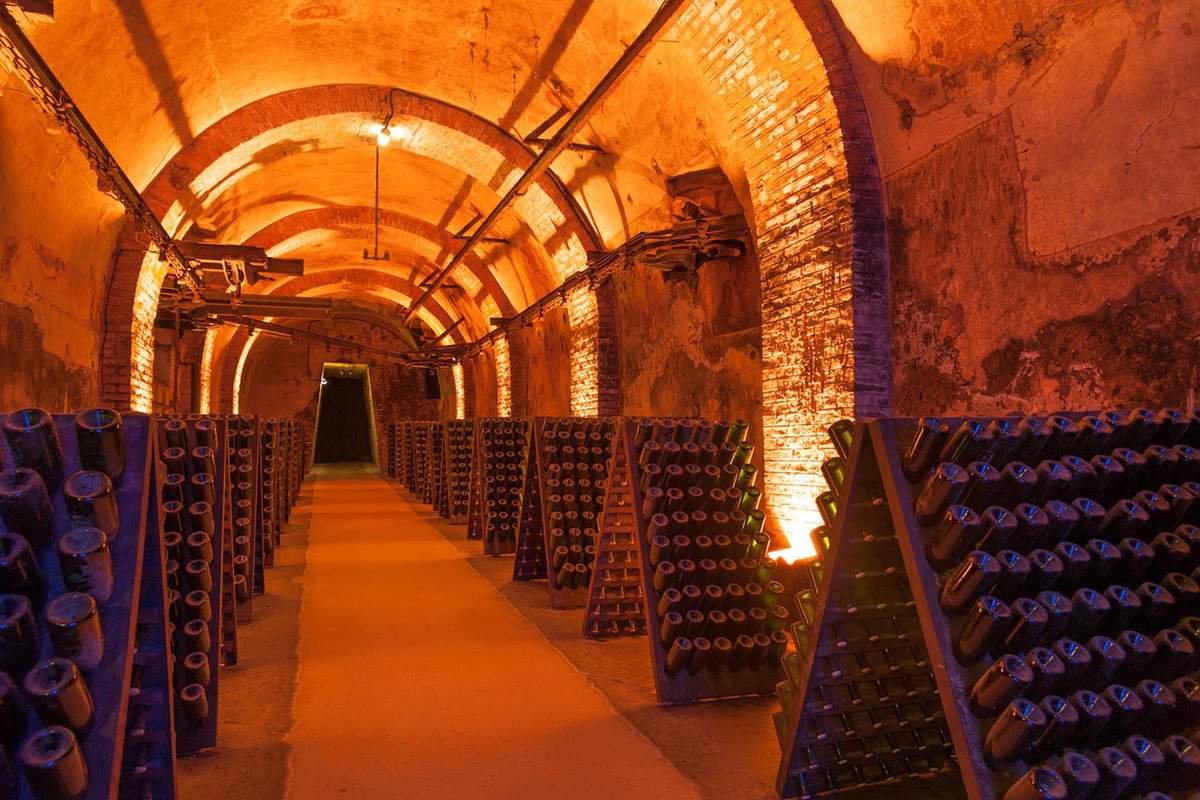 Inside view of a dim champagne cellar in Reims. There is orange tinted dim lights and rows of champagne