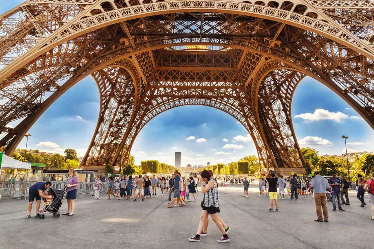 Landscape view from under the Eiffel Towers' legs of tourists walking on a sunny day
