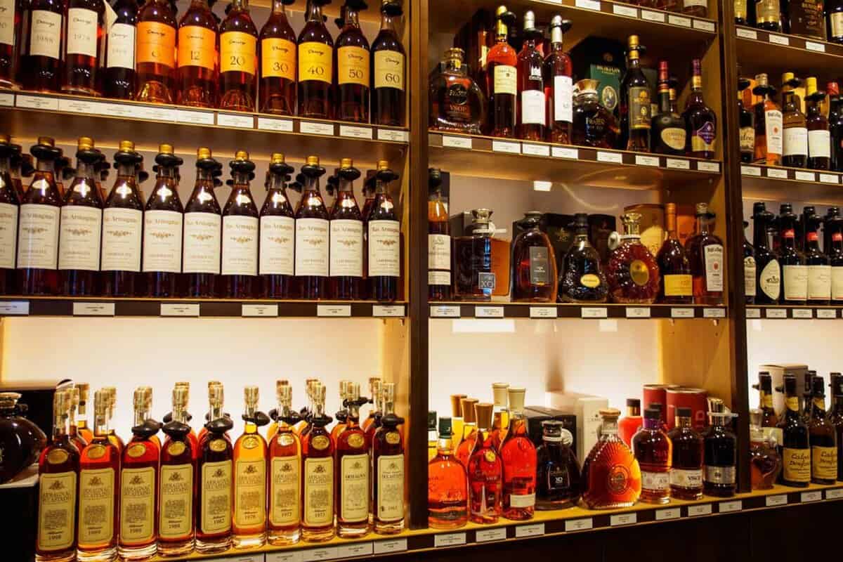 Wide angle detail of multiple bottles of Brandy, Cognac, and Amarginac from various brands on shelves at the Galeries Lafayette.