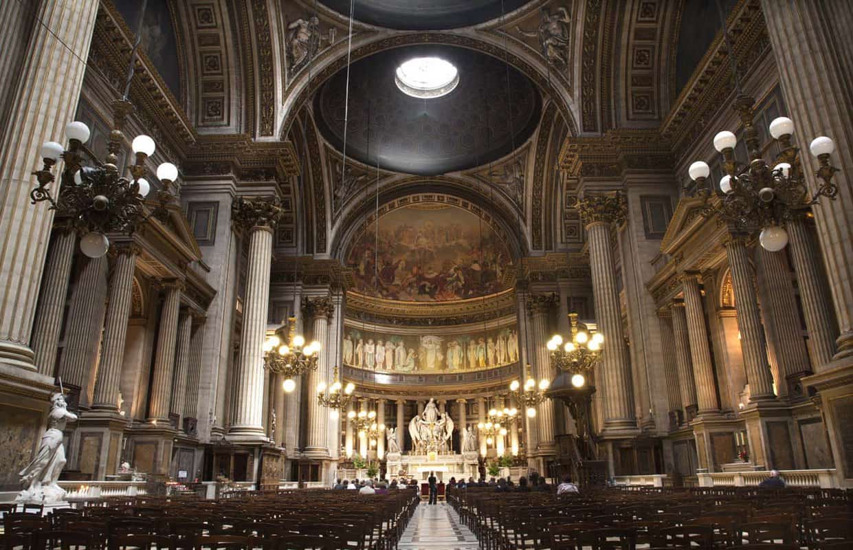 A view of inside the church from a distance where there are endless rows of chairs facing the centre of the angelic statues